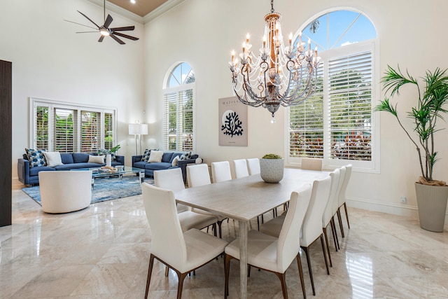 dining area with ceiling fan with notable chandelier, a high ceiling, a healthy amount of sunlight, and crown molding