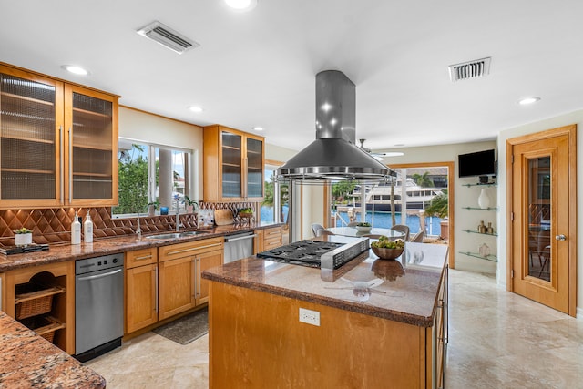 kitchen featuring island exhaust hood, backsplash, light stone countertops, sink, and a center island