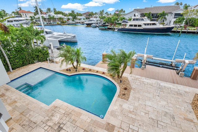 view of swimming pool featuring a water view, a boat dock, and a patio area