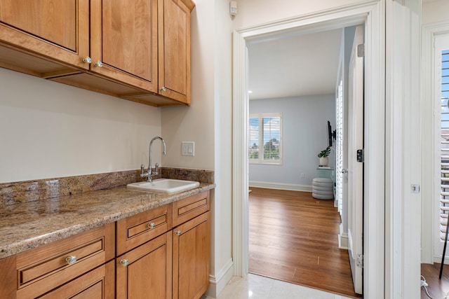 kitchen featuring light wood-type flooring, sink, and light stone counters