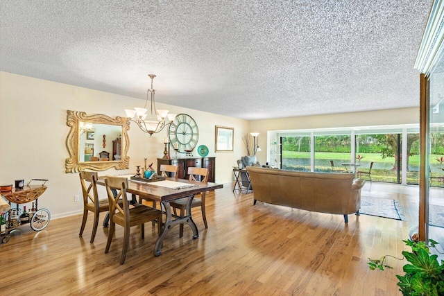 dining area featuring a textured ceiling, an inviting chandelier, and light wood-type flooring