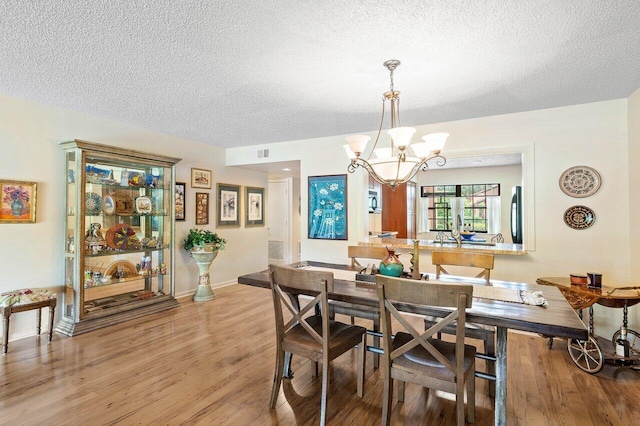 dining area with a notable chandelier, a textured ceiling, and hardwood / wood-style flooring