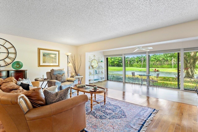 living room featuring light wood-type flooring, a textured ceiling, and plenty of natural light