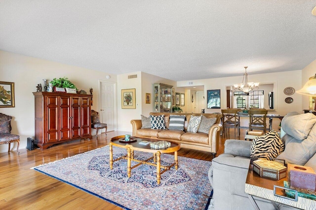 living room with wood-type flooring, a textured ceiling, and a chandelier