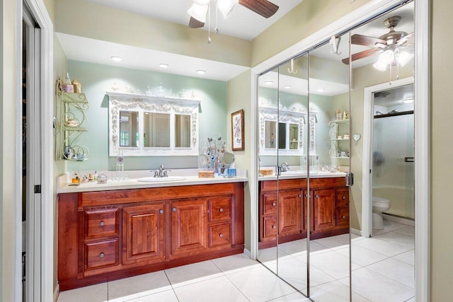 bathroom featuring a shower with door, tile patterned floors, toilet, vanity, and ceiling fan