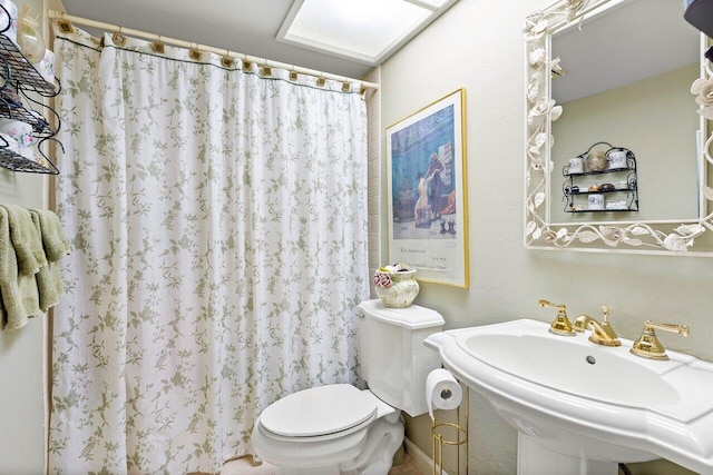 bathroom with toilet, walk in shower, and sink