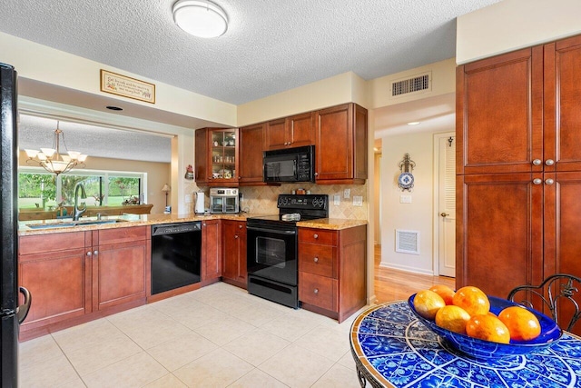 kitchen featuring decorative backsplash, black appliances, light tile patterned floors, and a textured ceiling