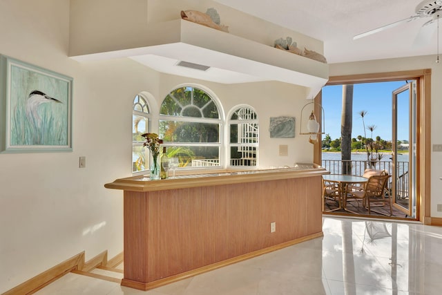 kitchen with a water view, ceiling fan, and light tile patterned flooring