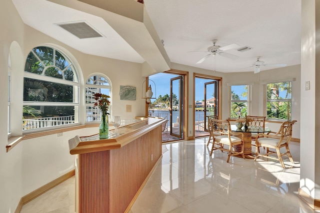 interior space with a water view, plenty of natural light, and ceiling fan