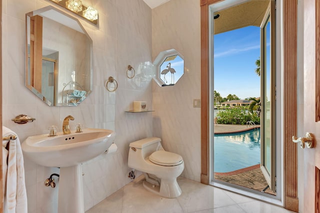 bathroom with tile patterned floors, toilet, and tile walls