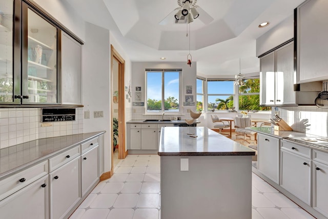 kitchen featuring a center island, white cabinets, a raised ceiling, sink, and tasteful backsplash