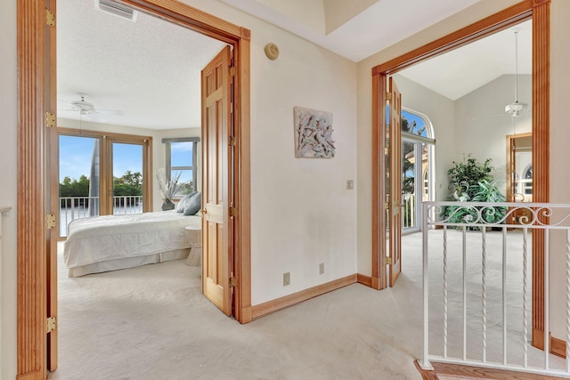 corridor with light colored carpet and vaulted ceiling