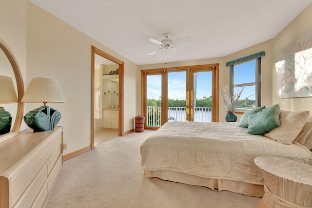 carpeted bedroom with ensuite bathroom, a water view, ceiling fan, access to exterior, and a textured ceiling