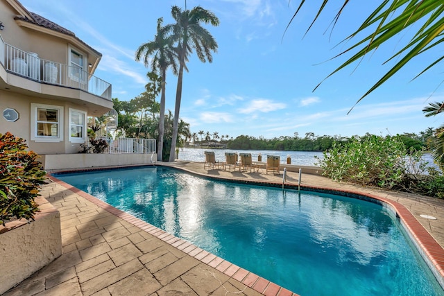 view of swimming pool featuring a water view and a patio area