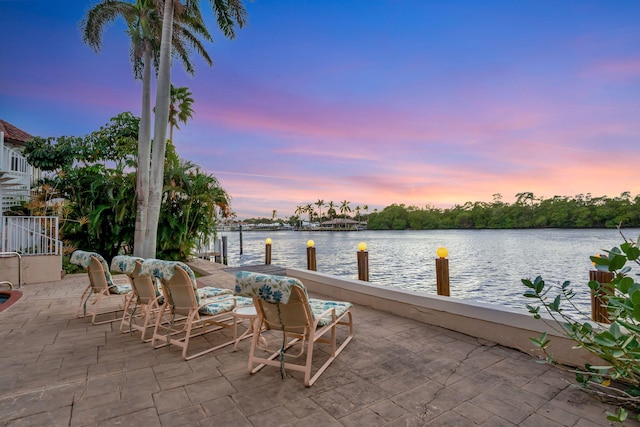 patio terrace at dusk with a water view and a boat dock