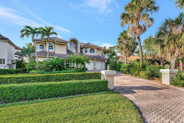 mediterranean / spanish-style house with a garage and a front lawn