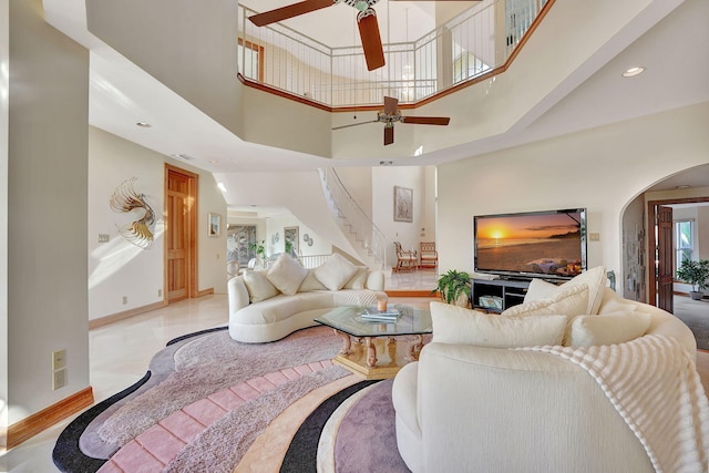 living room with a wealth of natural light, ceiling fan, and a high ceiling