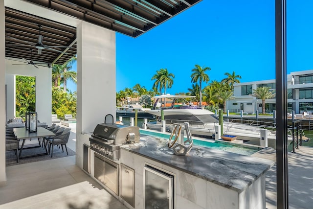 view of patio / terrace featuring grilling area, beverage cooler, a water view, exterior kitchen, and ceiling fan