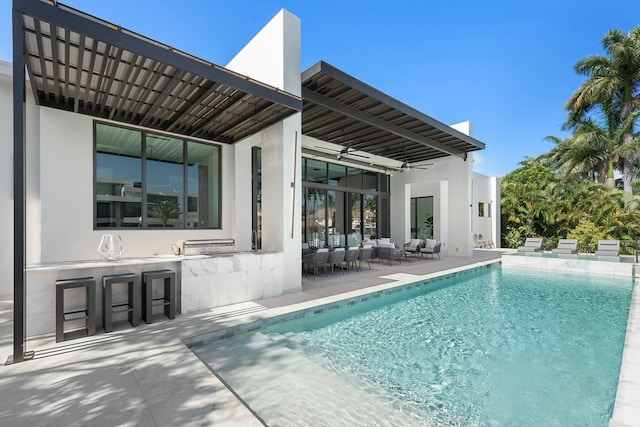 view of pool with ceiling fan, exterior bar, a patio area, and an outdoor hangout area