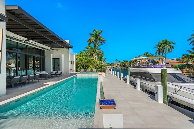 view of pool featuring a patio area, a water view, exterior bar, ceiling fan, and outdoor lounge area