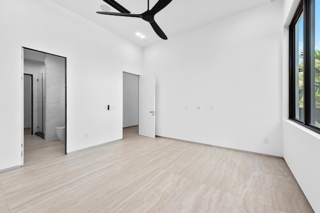 unfurnished bedroom featuring connected bathroom, ceiling fan, multiple windows, and light hardwood / wood-style flooring