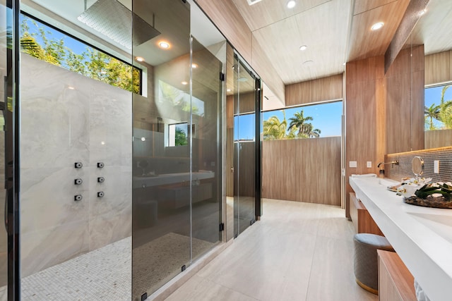 bathroom featuring vanity, wooden walls, a shower, and plenty of natural light