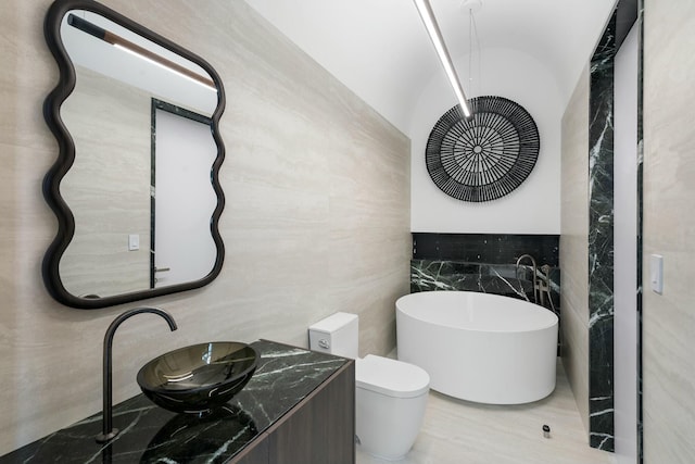 bathroom featuring a tub, sink, tile walls, and toilet