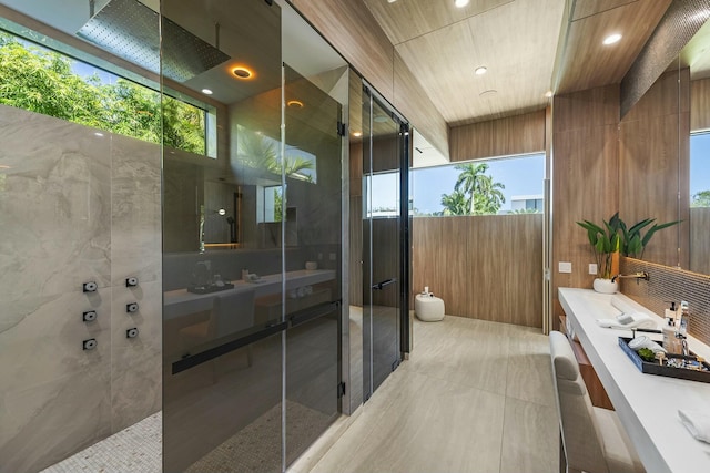 bathroom with tile walls, vanity, and walk in shower