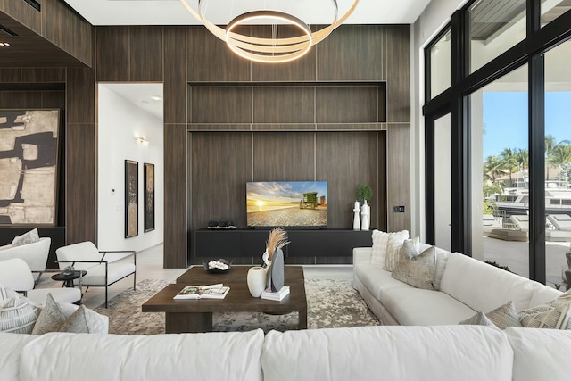 living room featuring a notable chandelier, a towering ceiling, and wooden walls