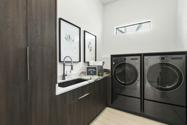 laundry area with sink, washer and dryer, cabinets, and light hardwood / wood-style floors