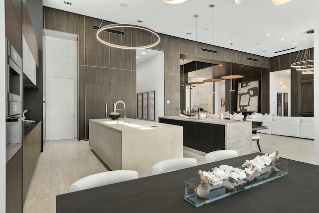 interior space with a kitchen bar, sink, a towering ceiling, hanging light fixtures, and a kitchen island with sink