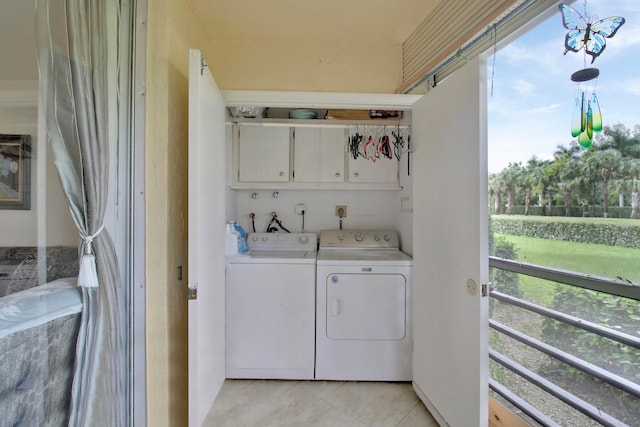 laundry room with cabinets, a healthy amount of sunlight, light tile patterned flooring, and washer and clothes dryer