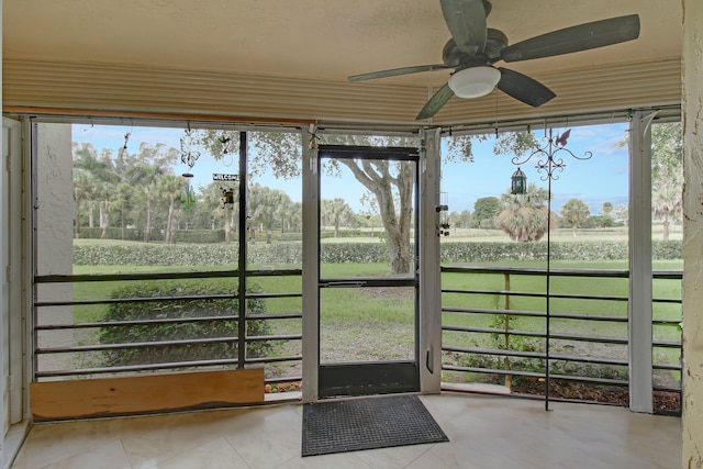 unfurnished sunroom with a rural view, ceiling fan, and a wealth of natural light