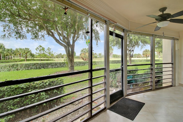 unfurnished sunroom featuring ceiling fan and a rural view