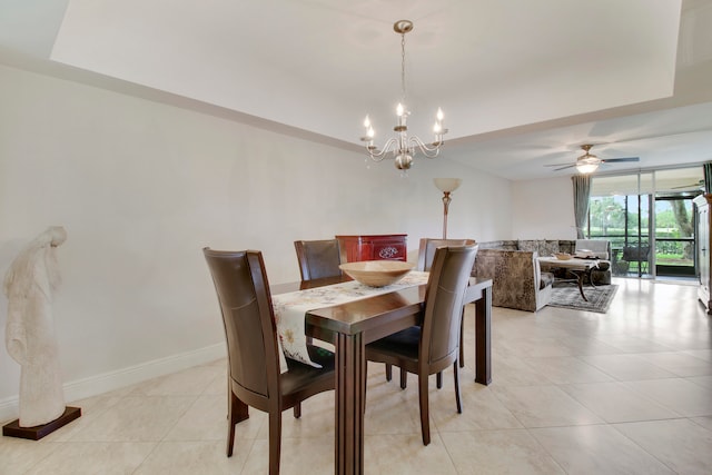 dining space featuring a tray ceiling, light tile patterned floors, and ceiling fan with notable chandelier