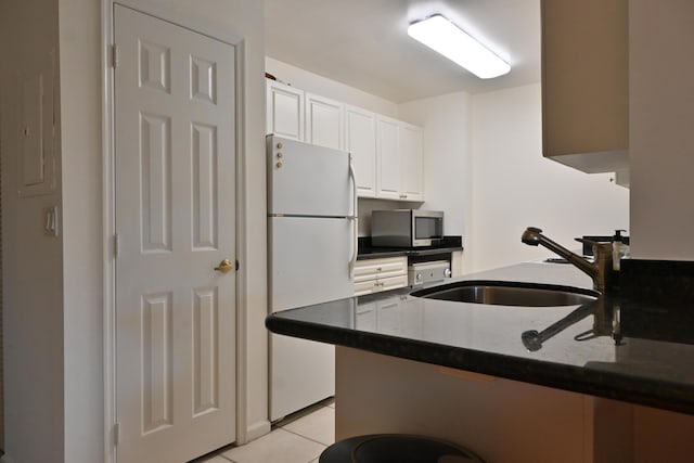 kitchen featuring white cabinets, kitchen peninsula, light tile patterned floors, and white fridge