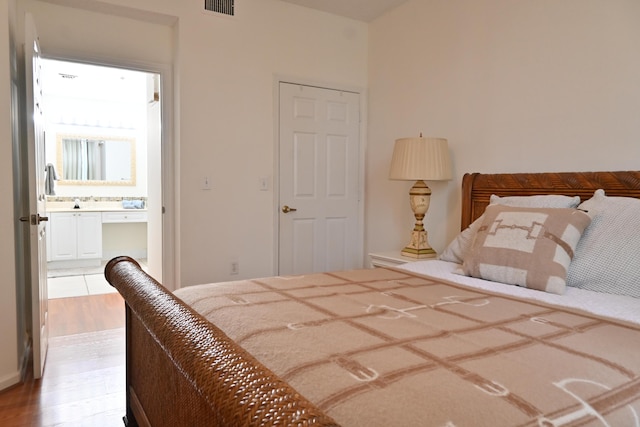 bedroom featuring ensuite bathroom and light hardwood / wood-style flooring