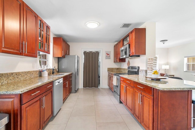 kitchen with light stone countertops, sink, stainless steel appliances, and light tile patterned flooring