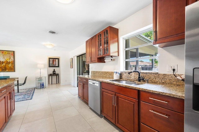 kitchen featuring light stone countertops, sink, light tile patterned floors, and appliances with stainless steel finishes