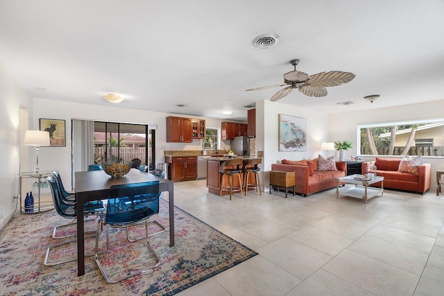 tiled dining area with ceiling fan and plenty of natural light