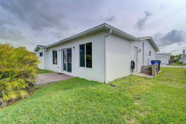 view of side of home with a patio and a lawn