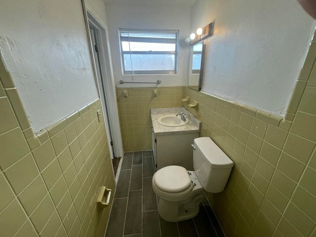 bathroom with vanity, toilet, and tile walls