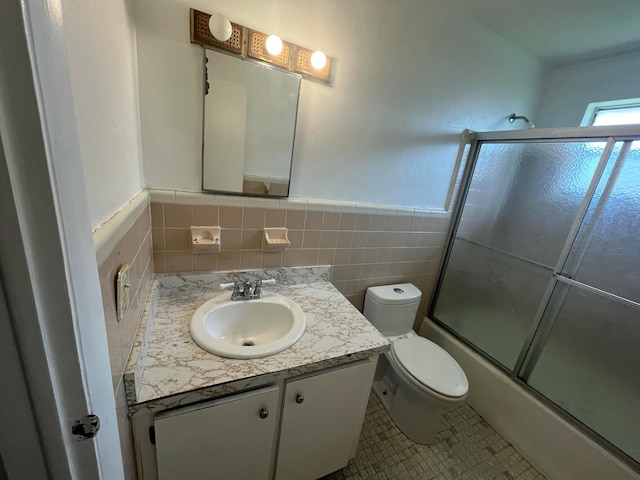 full bathroom featuring enclosed tub / shower combo, toilet, tile walls, tile patterned flooring, and vanity