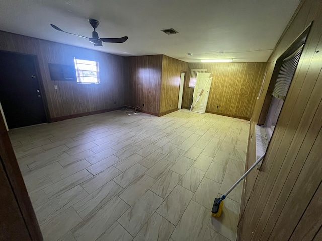 spare room featuring wood walls and ceiling fan