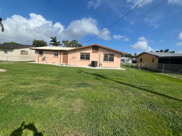 rear view of property with central AC and a lawn