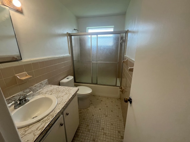 full bathroom with tile walls, combined bath / shower with glass door, vanity, and tile patterned floors