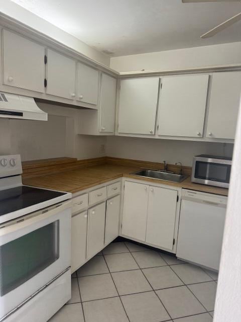 kitchen featuring white cabinets, extractor fan, light tile patterned flooring, sink, and white appliances