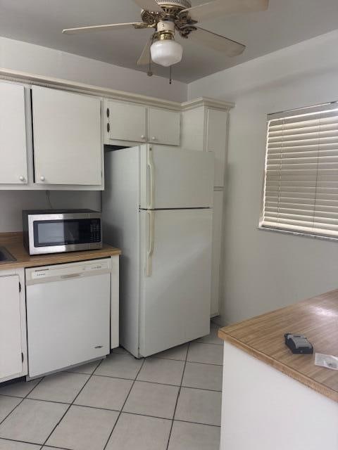 kitchen with white appliances, ceiling fan, light tile patterned flooring, and white cabinets