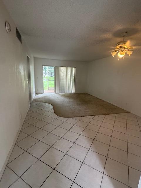 tiled spare room featuring a textured ceiling and ceiling fan