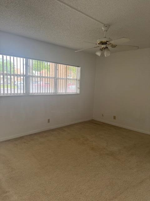 empty room with a textured ceiling, carpet, and ceiling fan